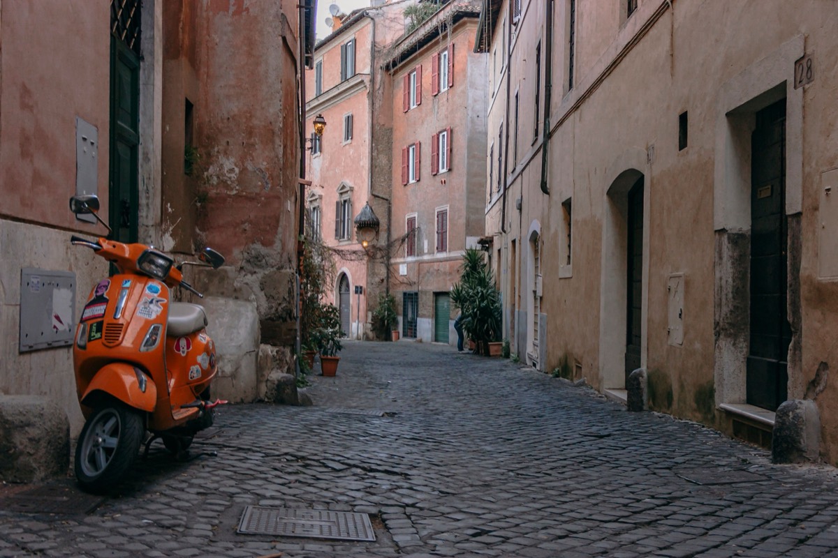 Scooter orange dans une rue pavée du Trastevere à Rome